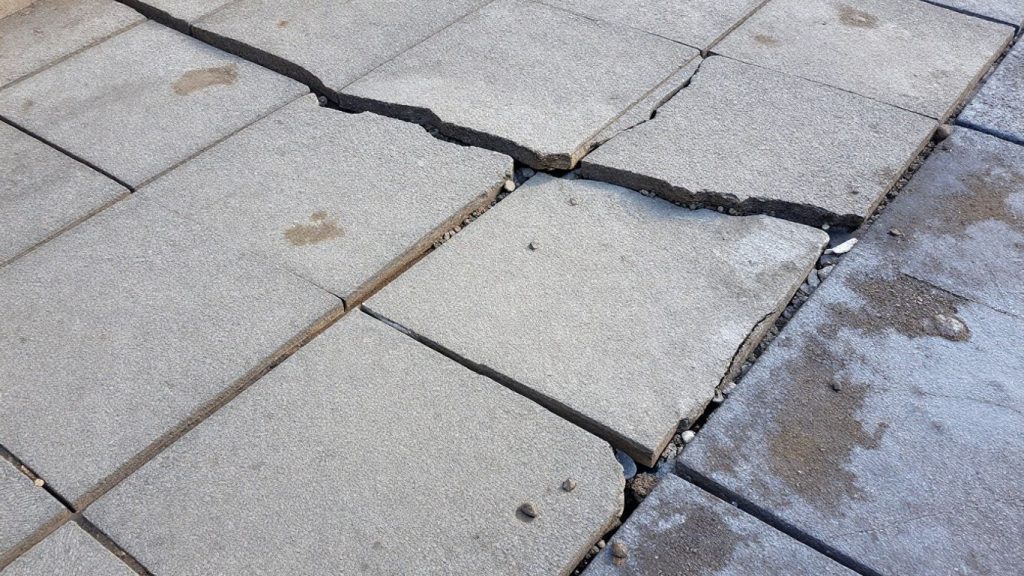 Cracked interlock patio damaged by frost heave.