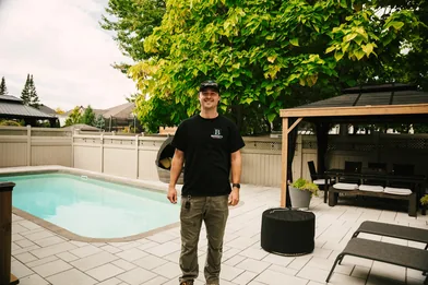 Completed Ottawa backyard showing an interlock patio surrounded by freshly mulched planting beds and clean lawn edges